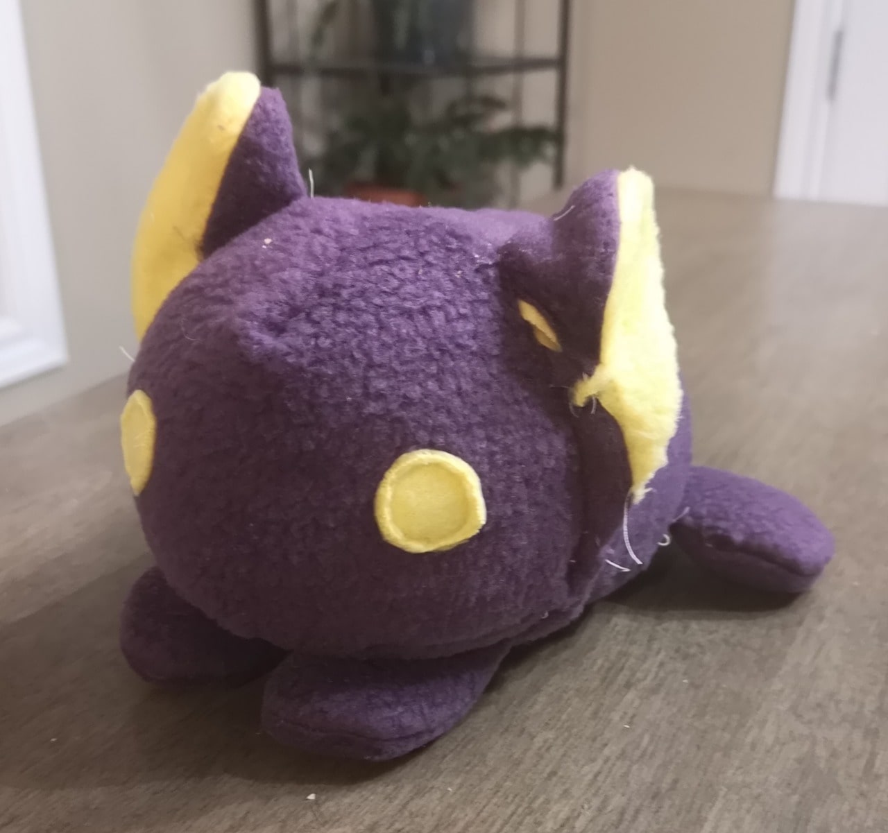 lumpy purple plush with round yellow eyes that vaguely resembles a cat